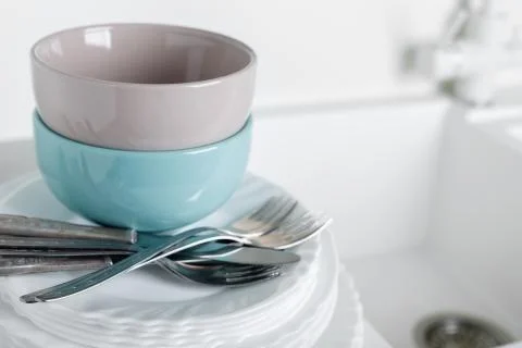 Stack of clean plates with forks, knives and glasses for serving on stone tab Foto stock