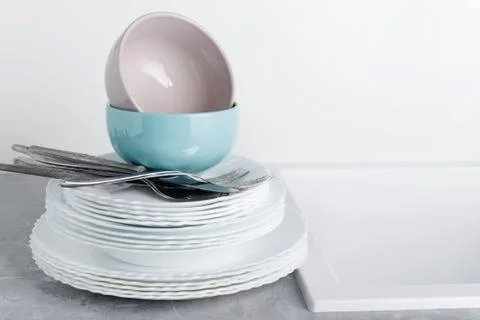 Stack of clean plates with forks, knives and glasses for serving on stone tab Stock Photos