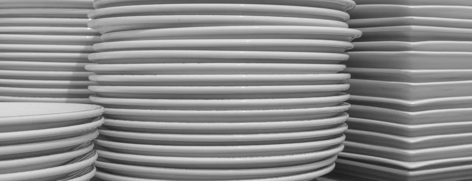 Stack of clean plates. Restaurant dishes on table. Ceramic dishware pile. Stock Photos