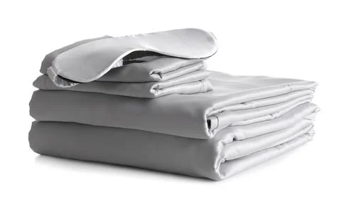 Stack of clean silky bed linen and sleeping mask isolated on white Stock Photos