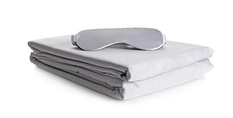 Stack of clean silky bed linen and sleeping mask isolated on white Stock Photos