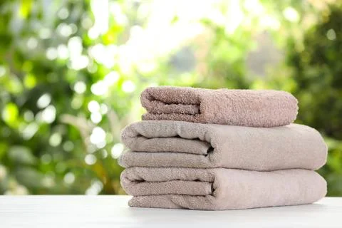 Stack of clean soft towels on table against blurred background. Space for tex 스톡 사진