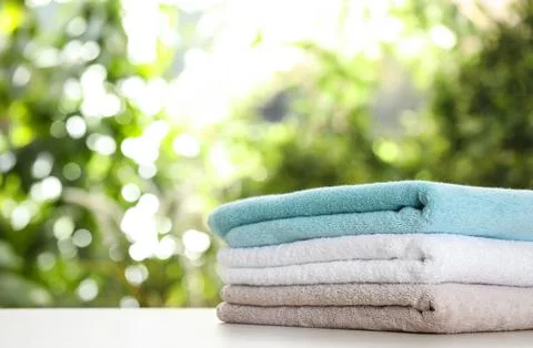 Stack of clean soft towels on table against blurred background. Space for tex Stockfoto's