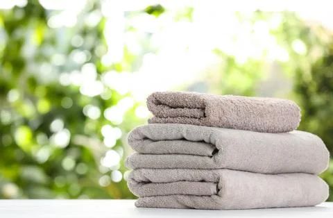 Stack of clean soft towels on table against blurred background. Space for tex 스톡 사진