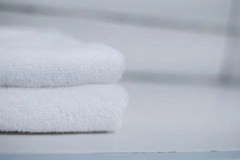 Stack of clean soft white towels on table against light grey background. Stock Photos