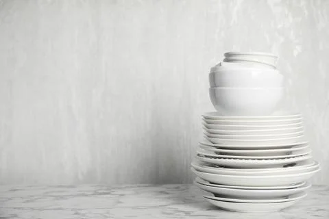 Stack of clean tableware on white marble table. Space for text 库存照片