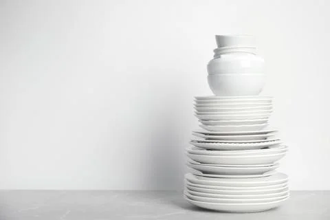 Stack of clean tableware on white table. Space for text 写真素材