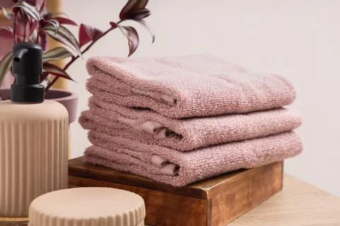 Stack of clean towels and bath supplies on table in bathroom, closeup Stock Photos