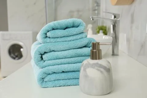 Stack of clean towels and soap dispenser on countertop in bathroom 스톡 사진