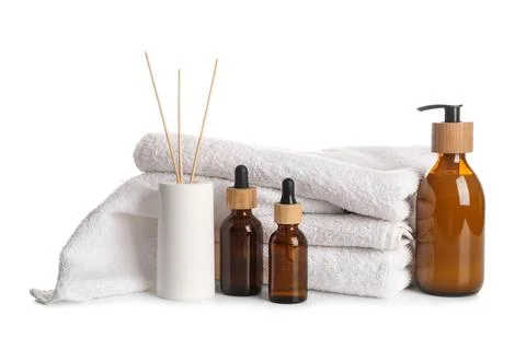 Stack of clean towels, aroma oils and reed diffuser isolated on white backgro Stock Photos