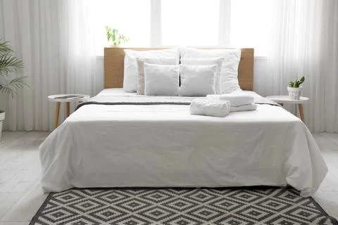 Stack of clean towels on bed in hotel room interior Stock Photos