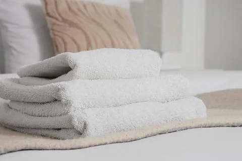 Stack of clean towels on bed in hotel room, closeup Stock Photos
