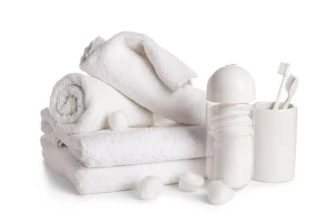 Stack of clean towels with cotton balls and toothbrushes isolated on white ba Stock Photos