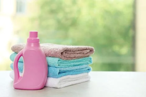 Stack of clean towels with detergent on table against blurred background. Spa 스톡 사진