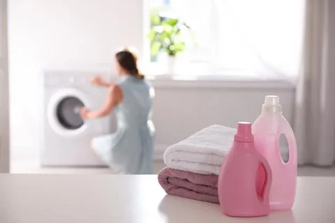 Stack of clean towels, detergents and blurred woman on background. Space for  Stockfoto's
