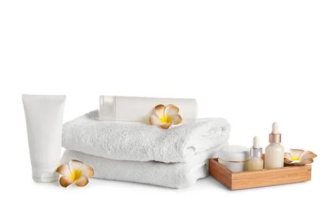 Stack of clean towels with flowers and skincare products isolated on white ba Stock Photos
