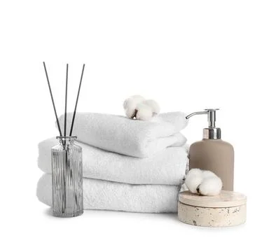 Stack of clean towels, reed diffuser and cotton flowers isolated on white bac Stock Photos