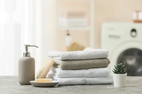 Stack of clean towels with soap dispenser and succulent plant Stock Photos