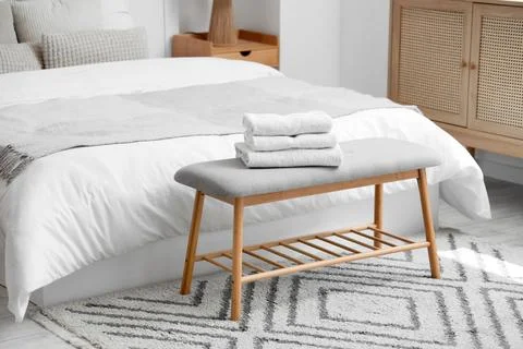 Stack of clean towels on soft bench in hotel room Stock Photos