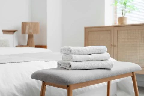 Stack of clean towels on soft bench in hotel room Stock Photos
