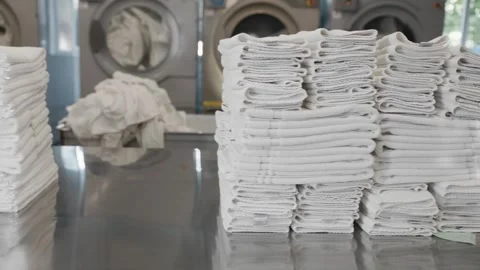 A stack of clean towels on a table in front of a washing machine Stock Footage 326248987