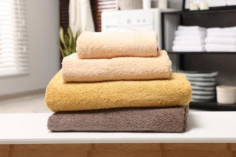 Stack of clean towels on white table in laundry room Stock Photos