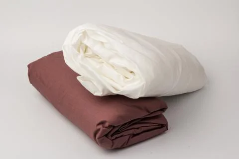 Stack of clean white and maroon bed sheets on white  background, closeup. Stock Photos