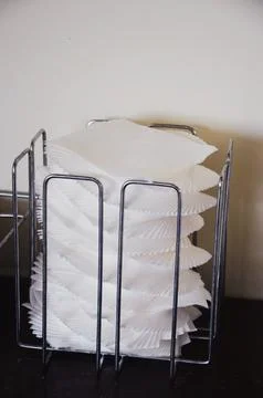 A stack of clean white square napkins stands on a dark table. Fotos Stock
