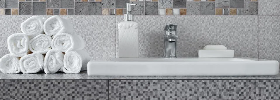 Stack of clean white towels on ceramic countertop in bathroom Stock Photos