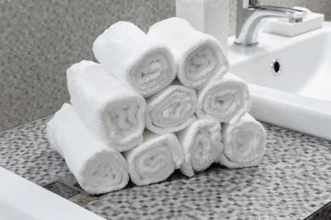 Stack of clean white towels on ceramic countertop in  bathroom Stock Photos