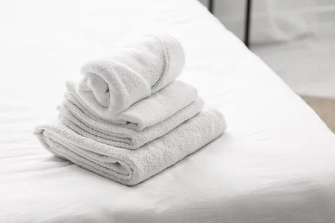 Stack of clean white towels on a freshly made bed, comfort, hygiene, and hosp Stock Photos