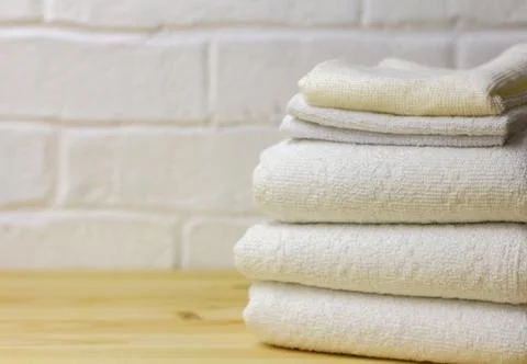 A stack of clean white towels lies on a wooden table. Stock Photos