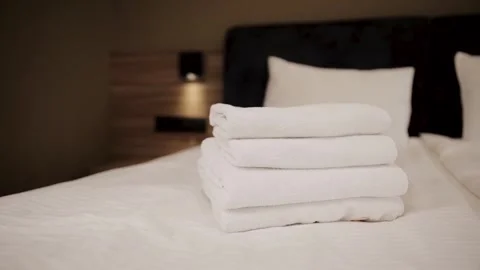 Stack of clean white towels resting on a hotel bed, hygiene, hospitality Stock Footage 324721743