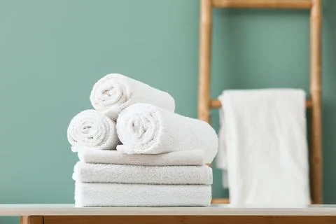 Stack of clean white towels with rolled towels on top in bathroom setting Stock Photos