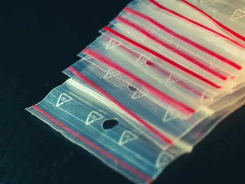 Stack of clear plastic bags with red seals and triangular cutouts 스톡 사진
