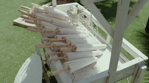 Stack of closed white parasols on vintage wooden wedding cart Stock Footage 312658450