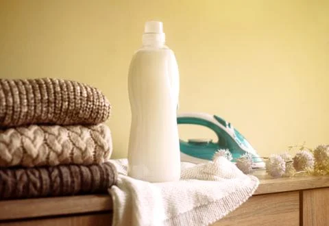 Stack of cloth, iron and blank white detergent bottle on the wood table Stock Photos