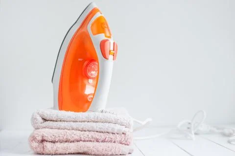Stack of clothes and electric iron, on white Stock Photos
