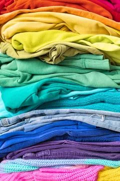 A stack of clothes in different colors. The concept of conscious clothing Stock Photos