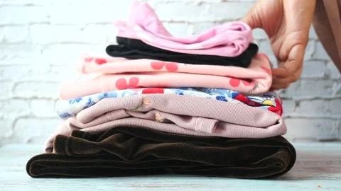 Stack of clothes on table indoor. Stock Footage 250436600