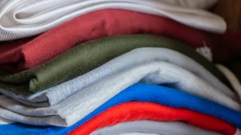 Stack of clothes in wardrobe. stack of colorful folded clothing items. Stock Photos