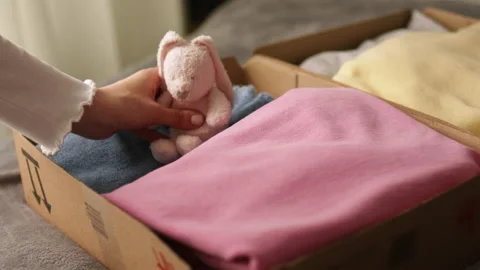 Stack clothing for donation in cardboard boxes with toy bunny. Stock Footage 195695828