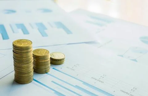 Stack of coin on business document graph. Money and financial concepts. Stock Photos