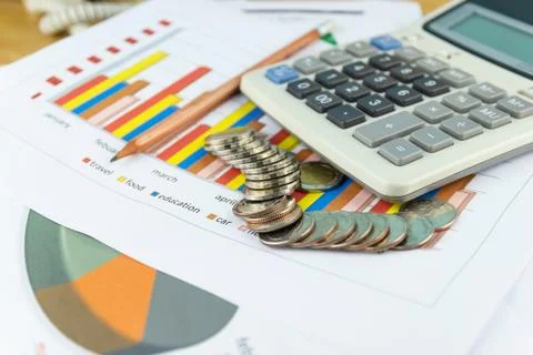 The stack of coin with business paper graphs and pencil with charts report Photos