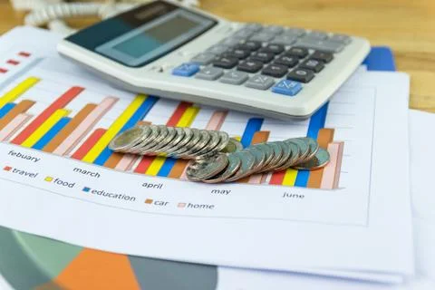 The stack of coin with business paper graphs and pencil with charts report Photos