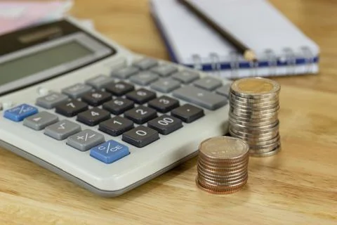 The stack of coin with calculator on wood table at office, concept Photos