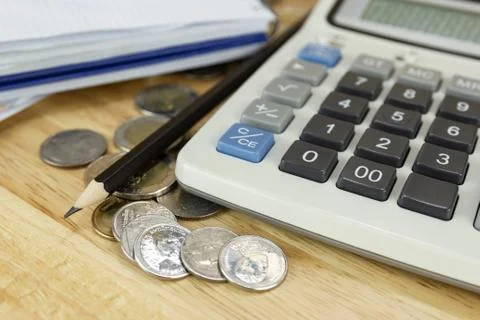 The stack of coin with calculator on wood table at office, concept of calcula Photos