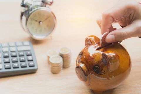 Stack coin with hand drop the coin into piggy bank. Financial, accounting and Stock Photos
