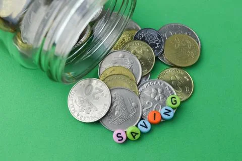 Stack of coins and alphabet bead with text SAVING. Financial concept. Stock Photos