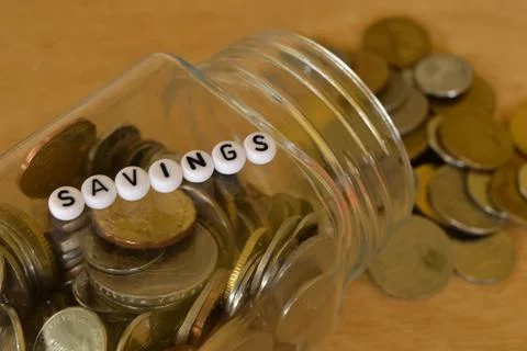 Stack of coins and alphabet beads with text SAVINGS. Financial concept. Stock Photos